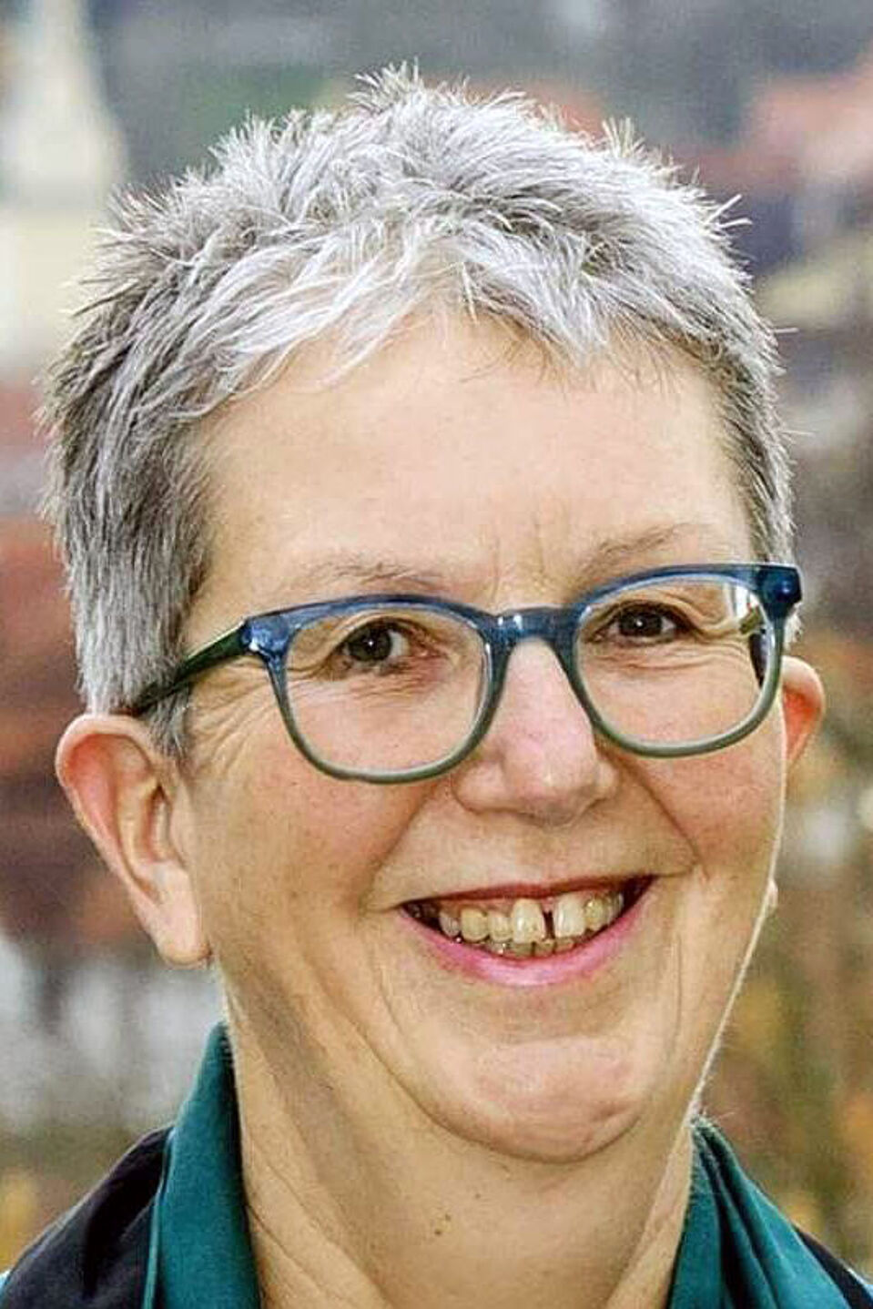 Dr. Uschi Sorg Porträtfoto einer lächelnden Frau mit kurzen grauen Haaren und blauer Brille.